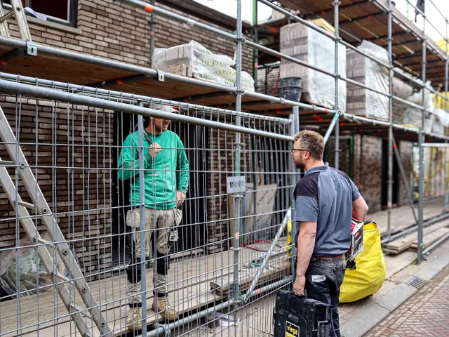 Twee monteurs van Merkx overleggen bij een bouwsteiger