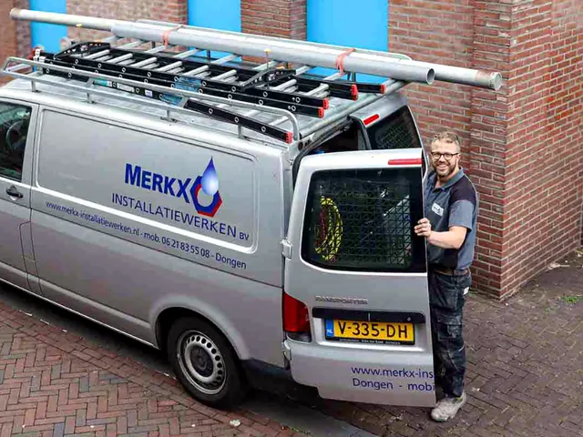 Monteur bij de bedrijfsbus van Merkx in een straat